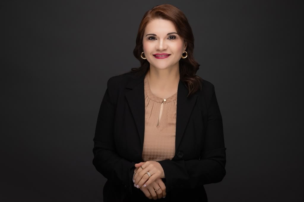 Adelina Salinas, DNP, smiling in a black blazer with her hands folded