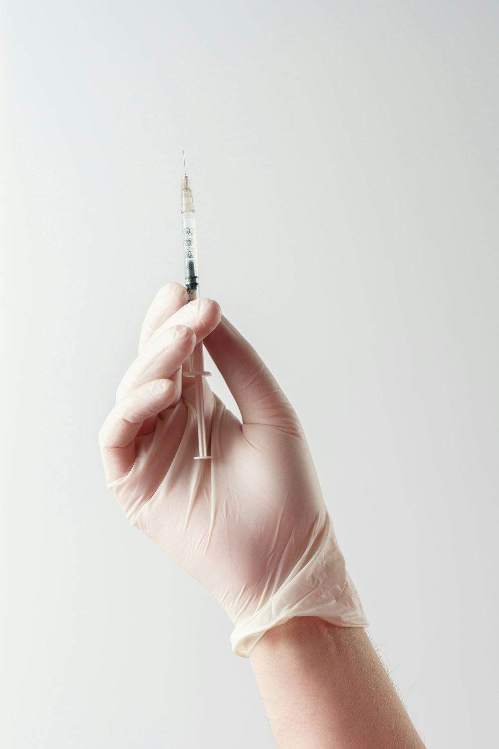 Gloved hand holding a fine cosmetic injection syringe